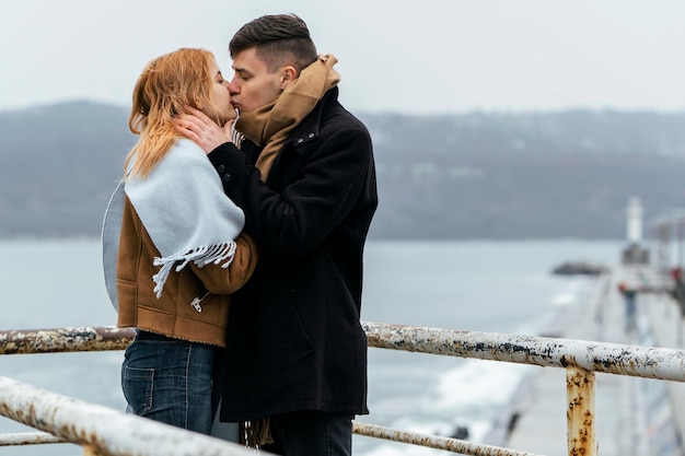 Side view of couple kissing by the lake during winter