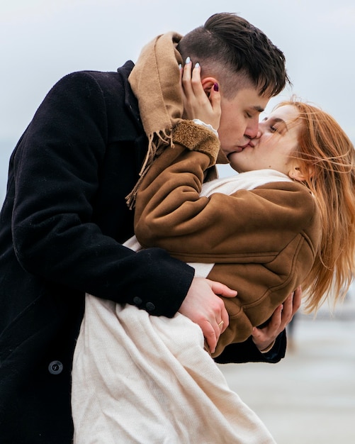 Side view of couple kissing each other by the lake during winter