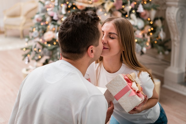 Side view of couple kissing with gifts in front of christmas tree