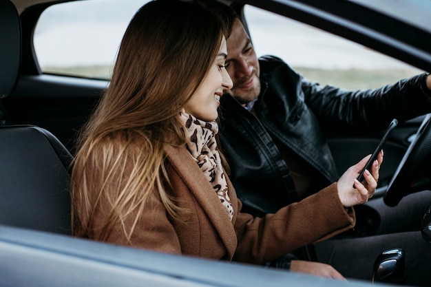 Side view of couple using smartphone in the car