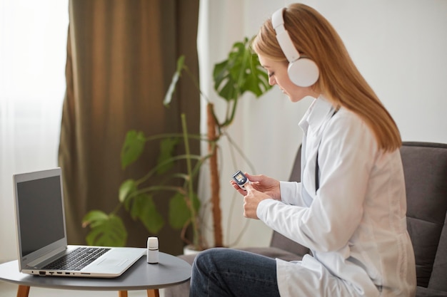 Side view of covid recovery center female doctor with headphones demonstrating how to use oximeter