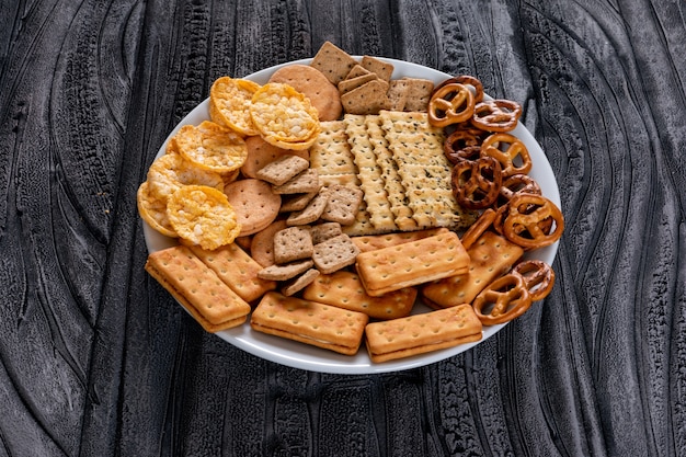 Free photo side view crackers in white plate on gray stone horizontal