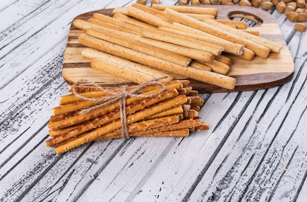 Side view of crackers on wooden cutting board on white  horizontal