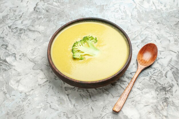 Free Photo side view of creamy broccoli soup in a brown bowl and spoon on gray table