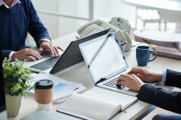 Side view of cropped unrecognizable business people working at common desk