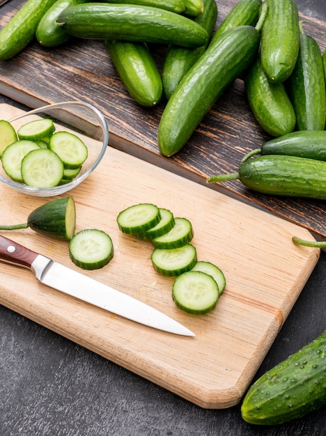 Free photo side view cucumber sliced on wooden cutting board