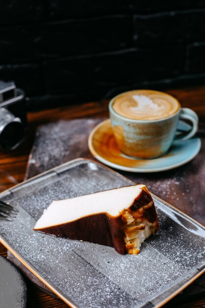 Side view of a cup of coffee latte served with cheesecake