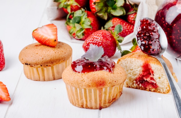 Side view cupcakes with strawberry jam basil and fresh strawberry on white background