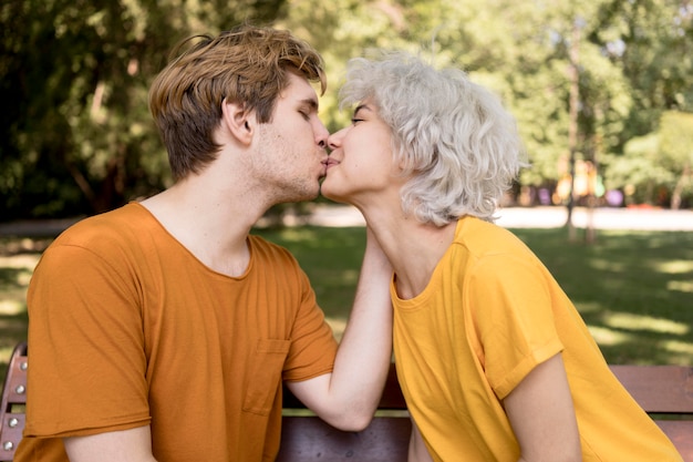 Free Photo side view of cute couple sharing a kiss in the park