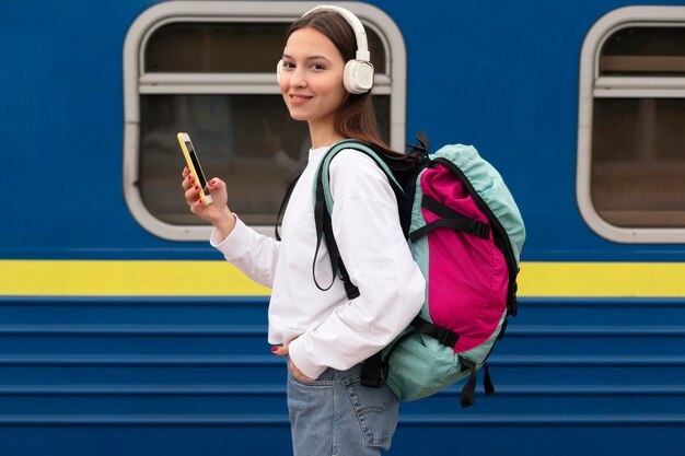 Side view cute girl at the railway station holding mobile phone