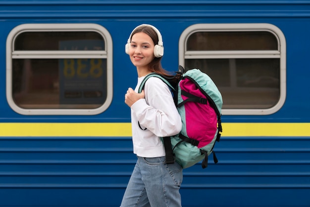 Side view cute girl at the railway station listening to music