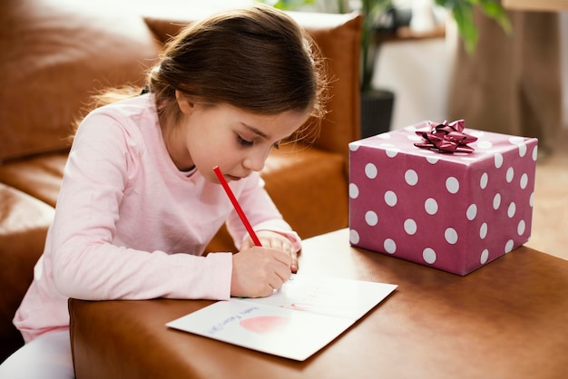 Side view of daughter drawing card for father's day with present