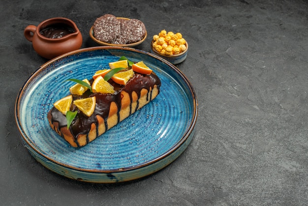 Free photo side view of delicious cakes on blue tray and biscuits on dark table