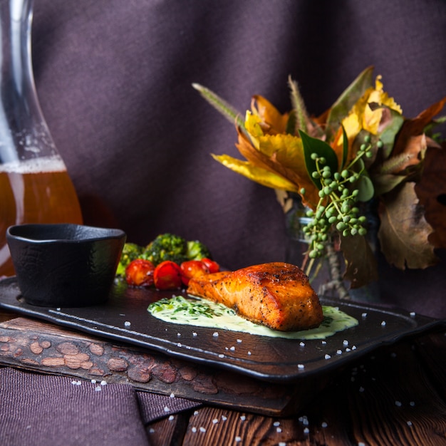 Free photo side view delicious meal in black tray on dark wooden background with decorations