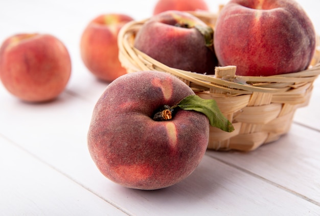 Side view of delicious peaches on a bucket with sweet peaches isolated on a white surface