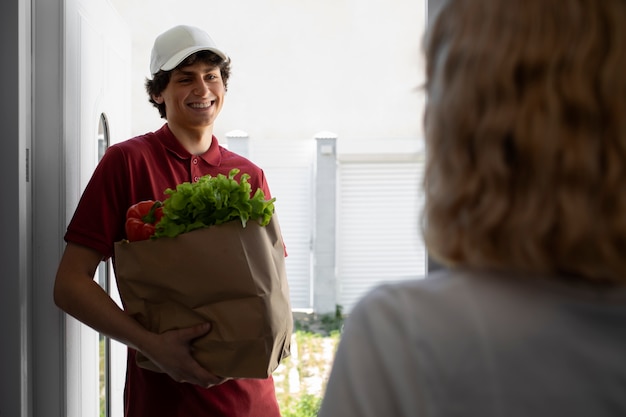 Side view delivery man holding groceries