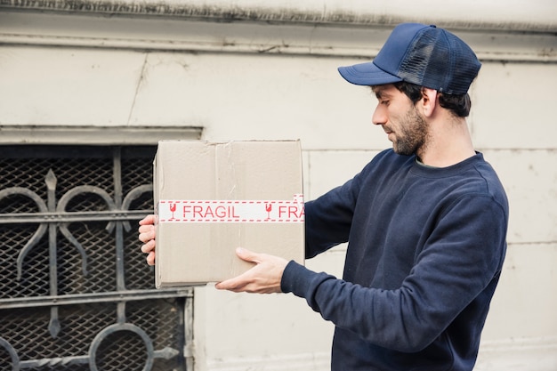 Free photo side view of a delivery man looking at parcel