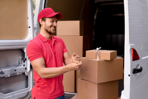 Free photo side view delivery man using hand sanitizer