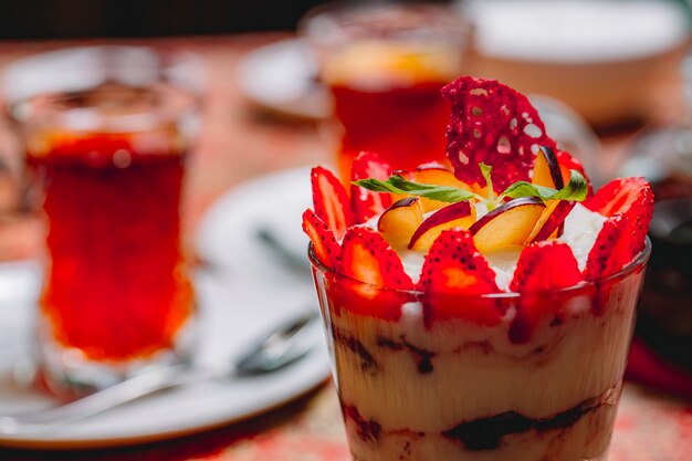 Side view dessert tiramisu with sliced strawberries and apple