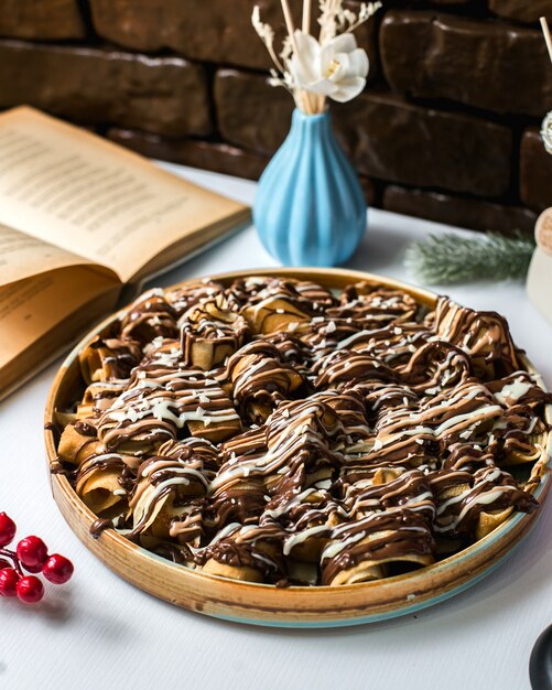 Side view of dessert with dough rolls covered with chocolate syrup on the table