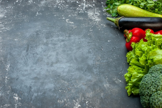 Side view of dinner preparation with fresh vegetables and green on the left side on dark background