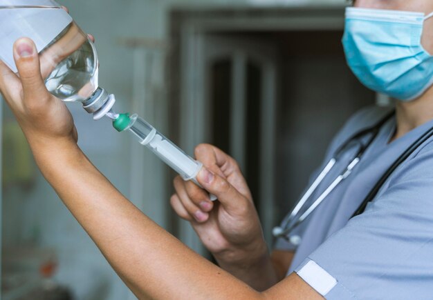 Side view of doctor filling up syringe with medicine