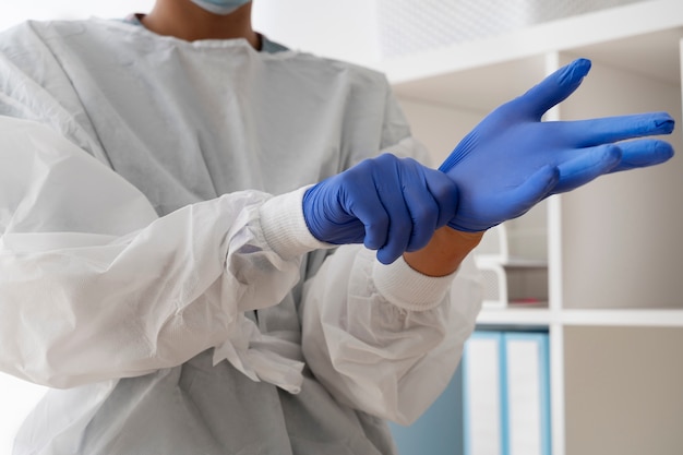 Free photo side view doctor putting on protection gloves