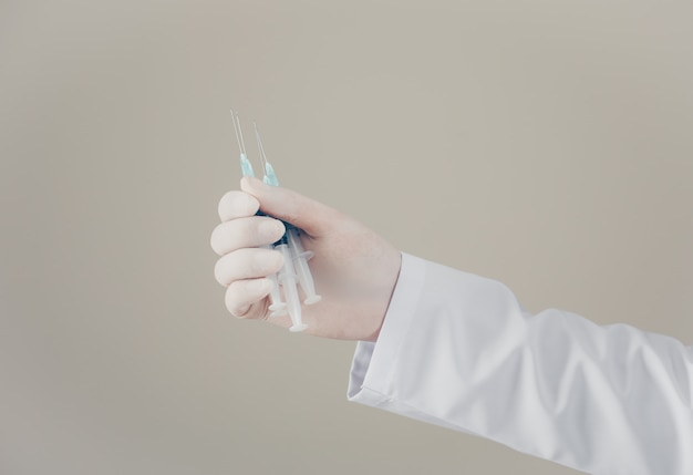 Side view doctor with gloves holding syringes in his hand. horizontal