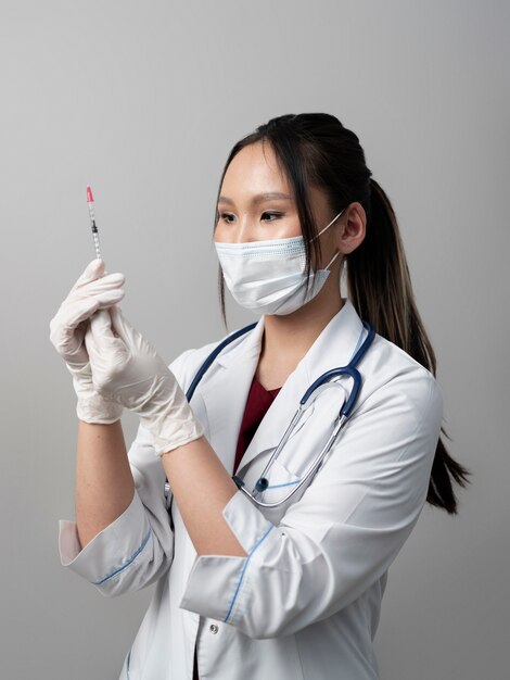 Side view doctor with mask holding syringe