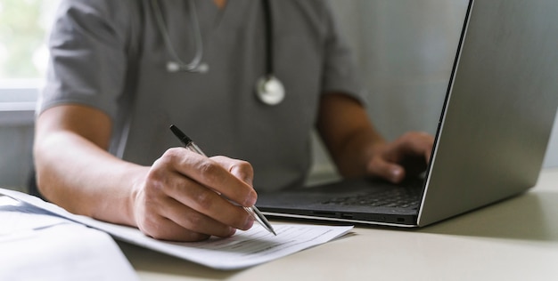 Free Photo side view of doctor with stethoscope working on laptop and writing on paper