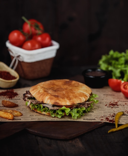 Side view of doner kebab with fried potatoes on a wooden cutting board