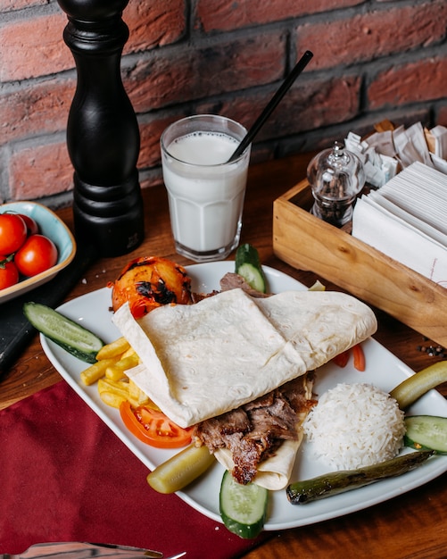 Side view of doner meat with french fries rice and vegetables on plate