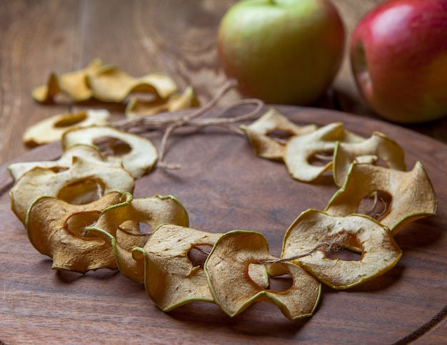 Free photo side view dried apples on round cutting board and fresh apples on wooden table