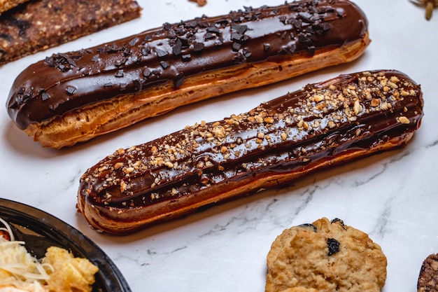 Free photo side view eclair choux dough filled with custard and topped with chocolate icing