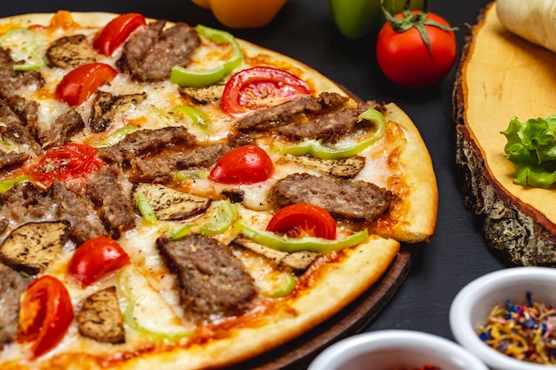 Side view eggplant pizza with grilled slices of red meat bell pepper cheese and tomato on the table