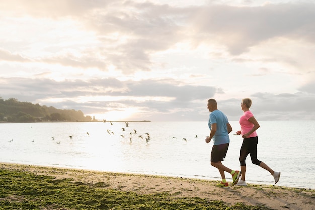 Side view of elder couple jogging on the beach