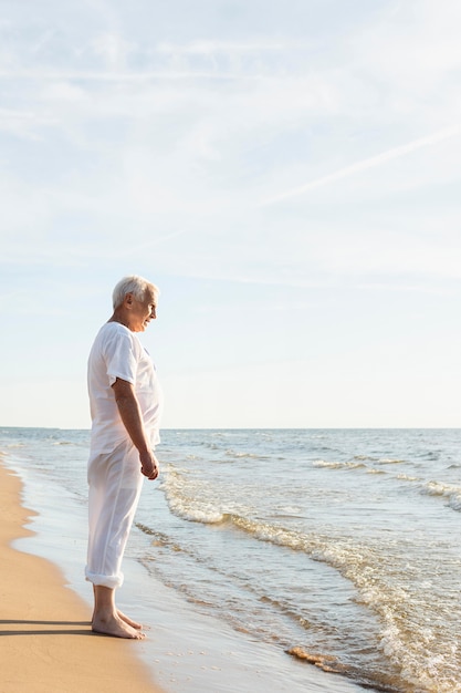 Side view of elder man resting while admiring the beach view