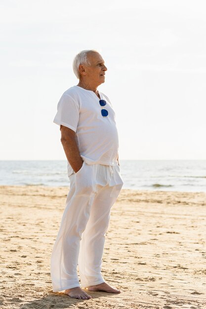 Side view of elder man with sunglasses admiring the sun at the beach