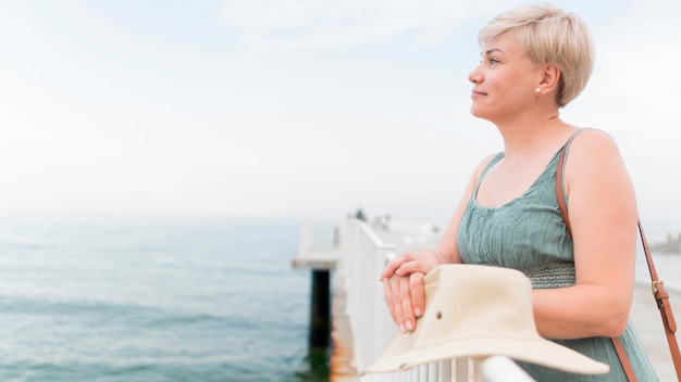 Side view of elder tourist woman posing while at the beach