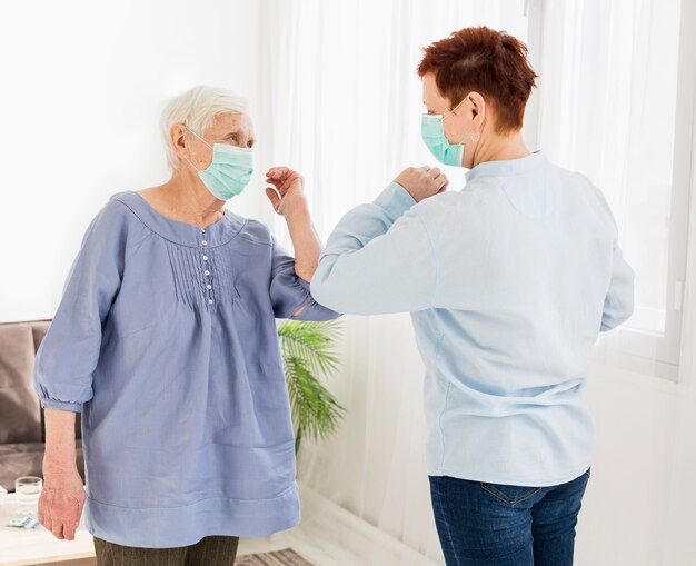 Side view of elder women saluting each other by touching elbows