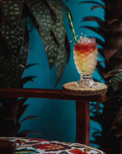 Free Photo side view of exotic cocktail in embossed glass in a wooden stand on green wall