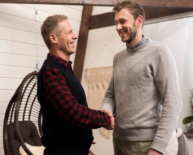 Free photo side view of father and son shaking hands