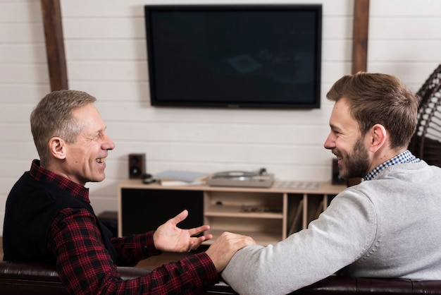 Side view of father and son sitting together on sofa