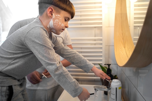 Free photo side view father teaching kid how to shave