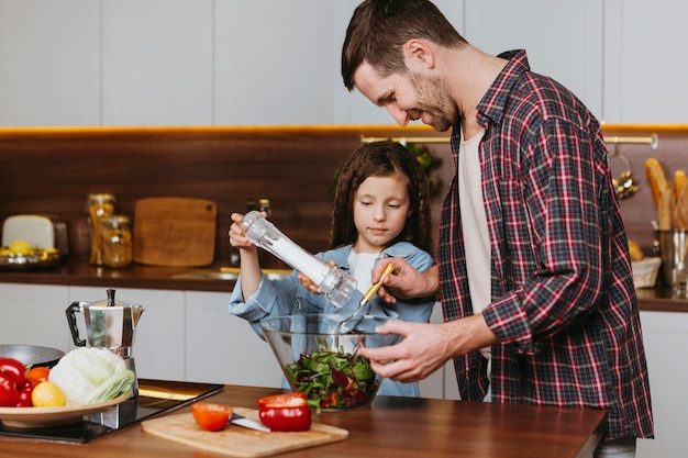 Side view of father with daughter preparing food in the kitchen