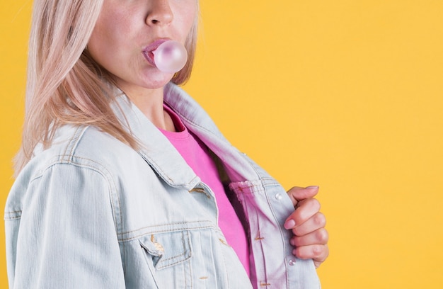 Free photo side view female blowing bubble gum