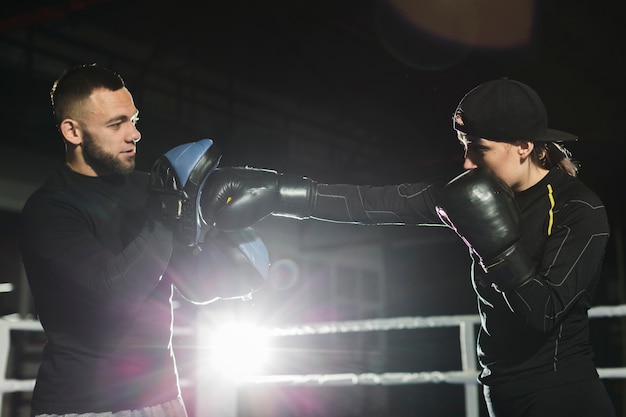 Free Photo side view of female boxer practicing in the ring with trainer