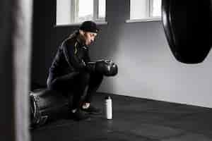 Free photo side view of female boxer resting with flask