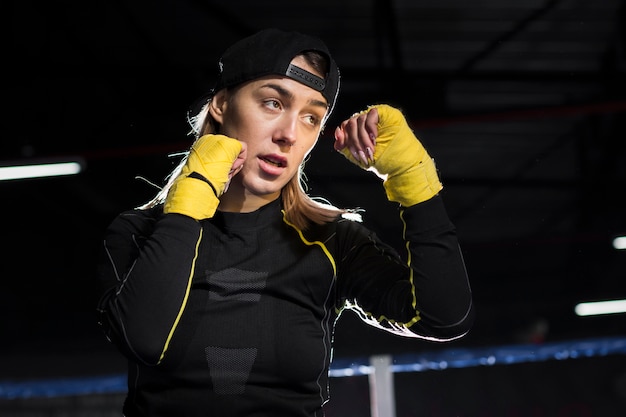 Side view of female boxer in the ring wearing protective gloves