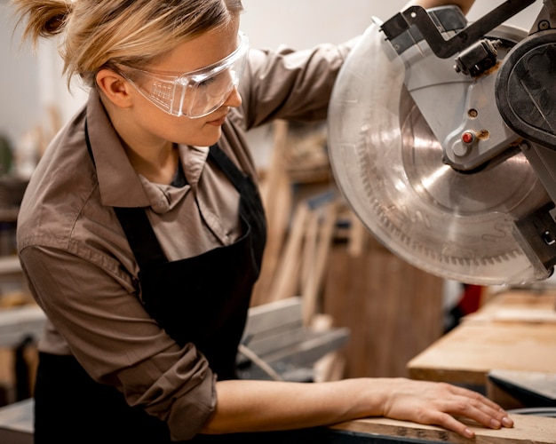 Free photo side view of female carpenter with tool and safety glasses